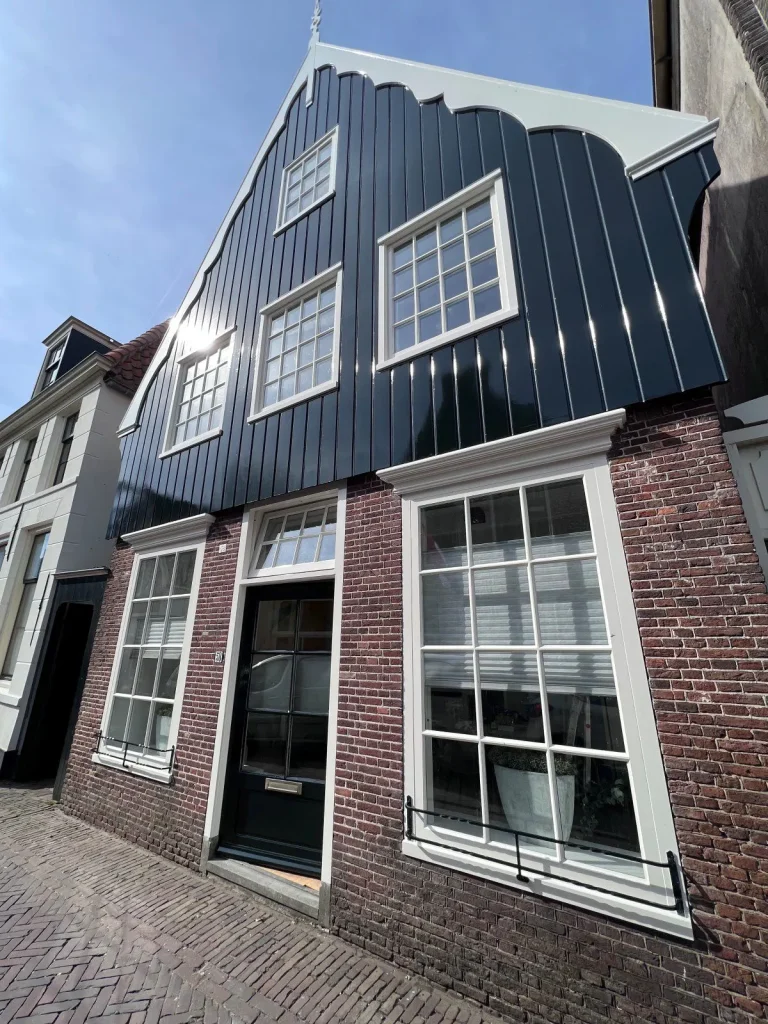 Zijaanzicht van de donkere houten topgevel met wit geschilderde kozijnen van woning in De Rijp