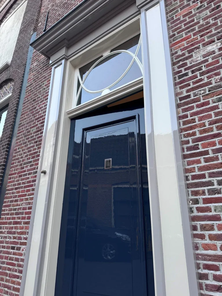 Vooraanzicht van de donkerblauwe voordeur met decoratief glas-in-lood bovenlicht, Edam