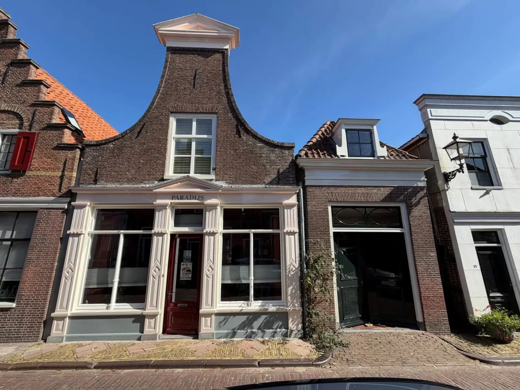Straatbeeld Lingerzijde in Edam met pand Paradijs en de zwarte voordeur van nummer 13 ernaast
