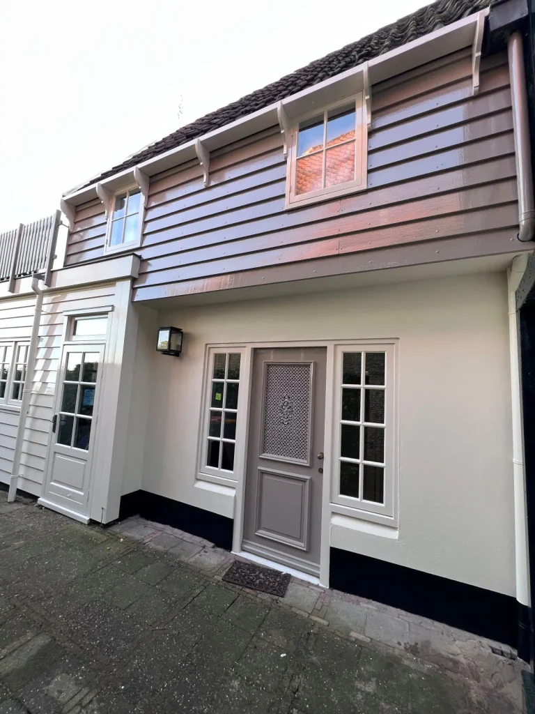 Grijs-taupe geschilderde gevel met voordeur en beschoeiing in De Rijp