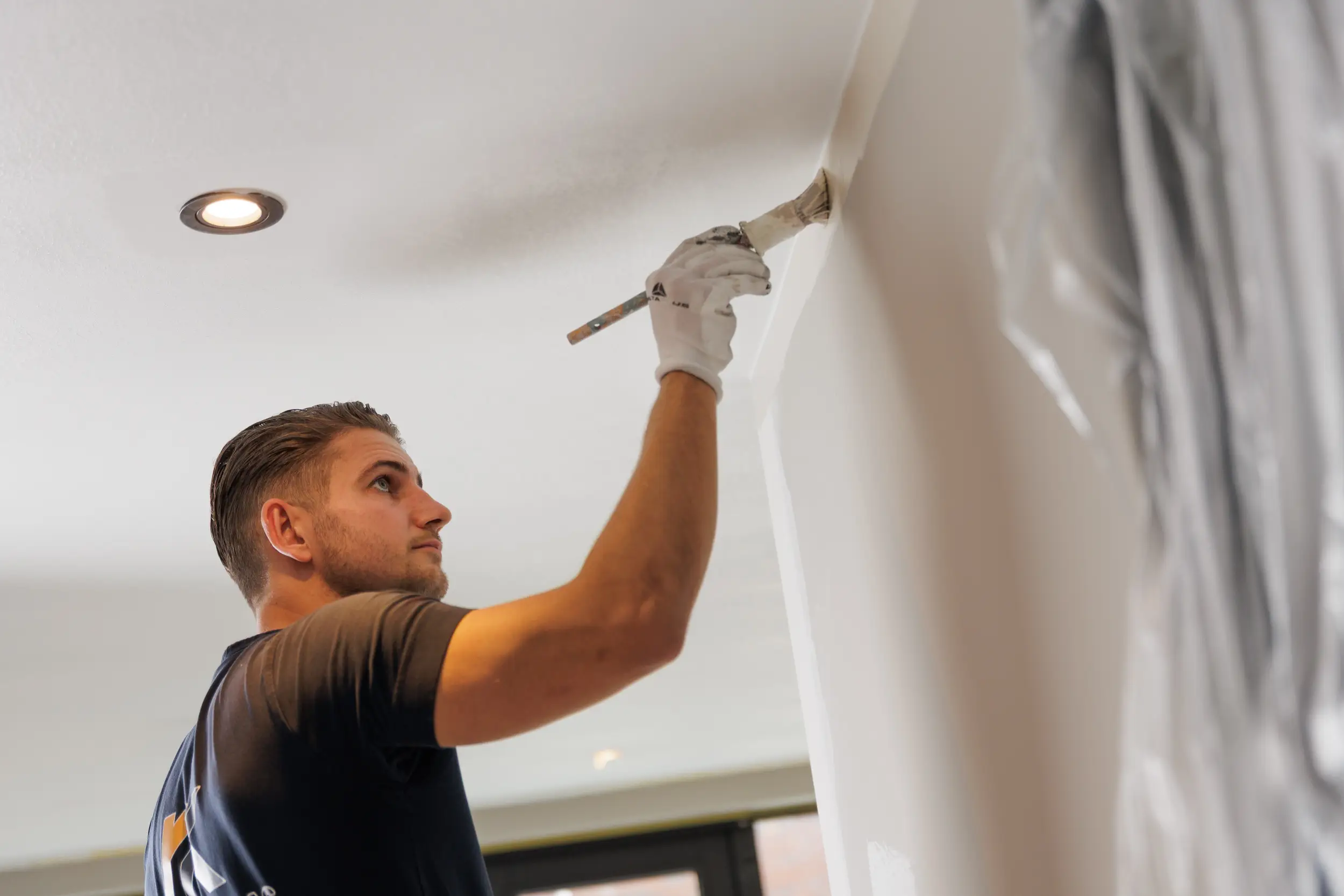 Schilder brengt verf aan op een wand in een woonkamer